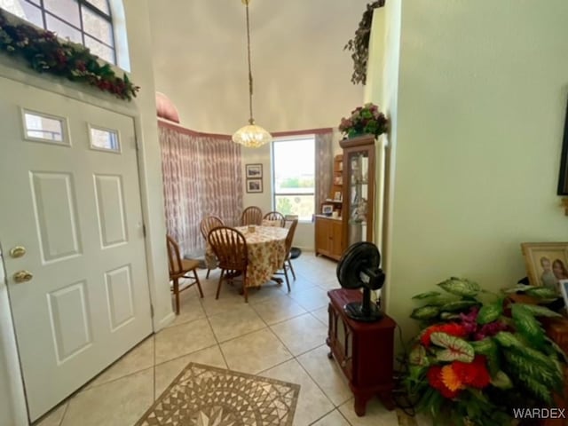 dining space with light tile patterned flooring, a towering ceiling, and an inviting chandelier