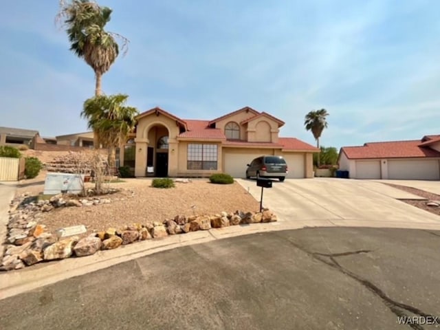 mediterranean / spanish-style house featuring driveway, a tiled roof, a garage, and stucco siding