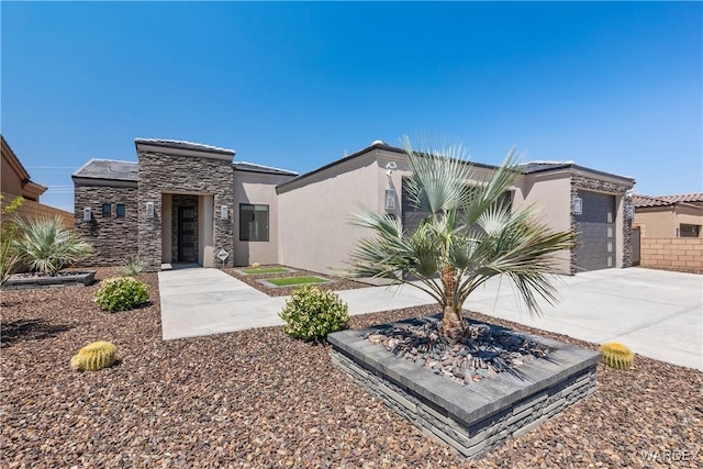 view of front of house with stone siding, an attached garage, concrete driveway, and stucco siding