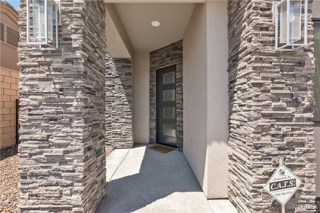 view of exterior entry with stone siding and stucco siding