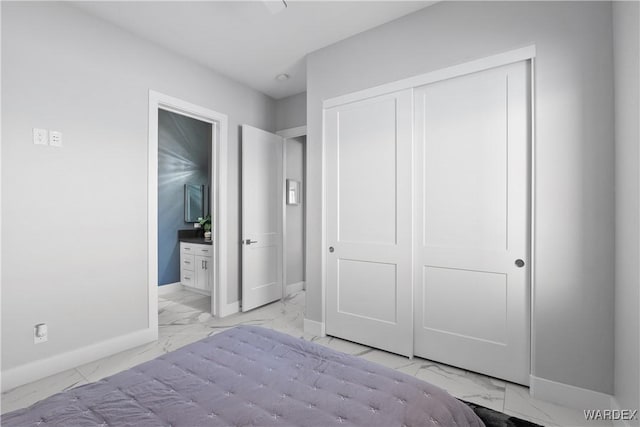 unfurnished bedroom with a closet, marble finish floor, baseboards, and ensuite bathroom