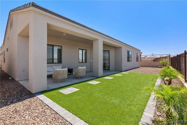 back of property with a yard, a fenced backyard, a patio, and stucco siding