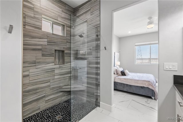 bathroom with marble finish floor, tiled shower, ceiling fan, and ensuite bathroom