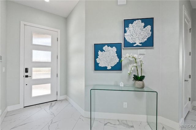 entrance foyer featuring marble finish floor, plenty of natural light, and baseboards