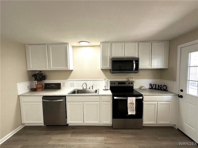 kitchen with white cabinetry, stainless steel appliances, dark wood-type flooring, and a sink