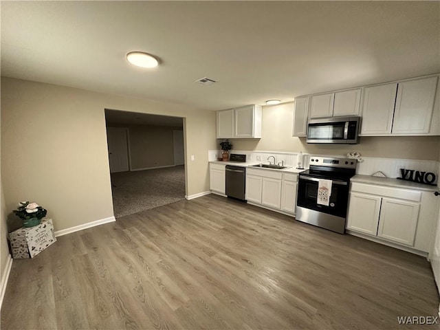 kitchen with stainless steel appliances, light countertops, visible vents, a sink, and baseboards