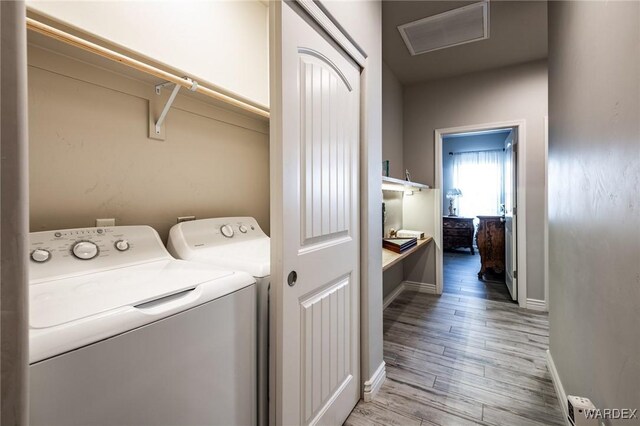 laundry area featuring laundry area, baseboards, washer and clothes dryer, and wood finished floors