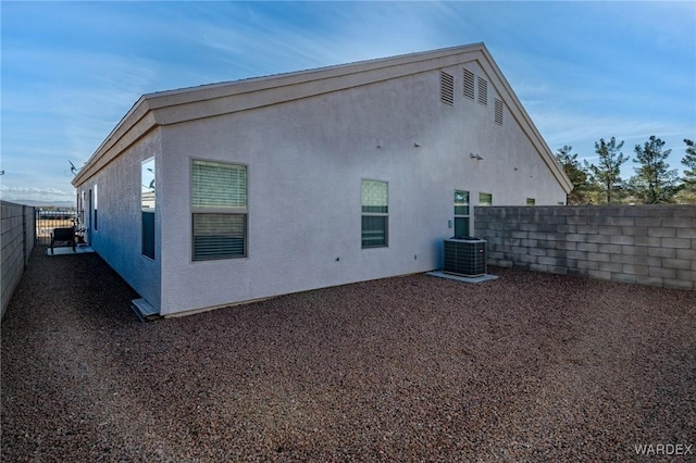 rear view of property featuring cooling unit, fence, and stucco siding