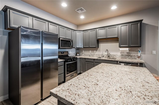 kitchen with light stone counters, recessed lighting, visible vents, appliances with stainless steel finishes, and a sink