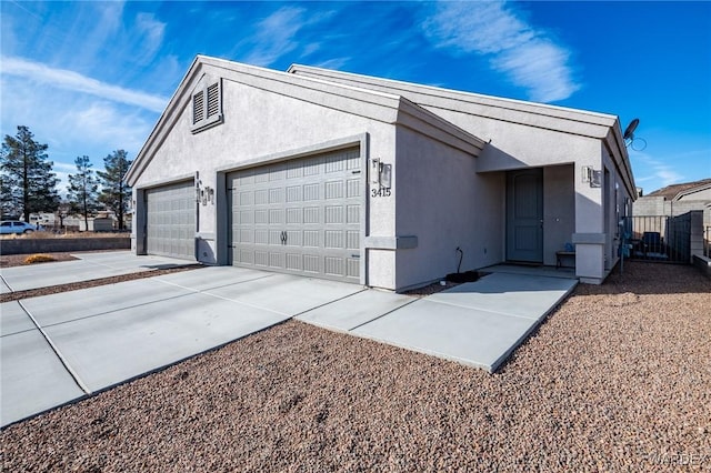 view of side of home with concrete driveway, an attached garage, and stucco siding