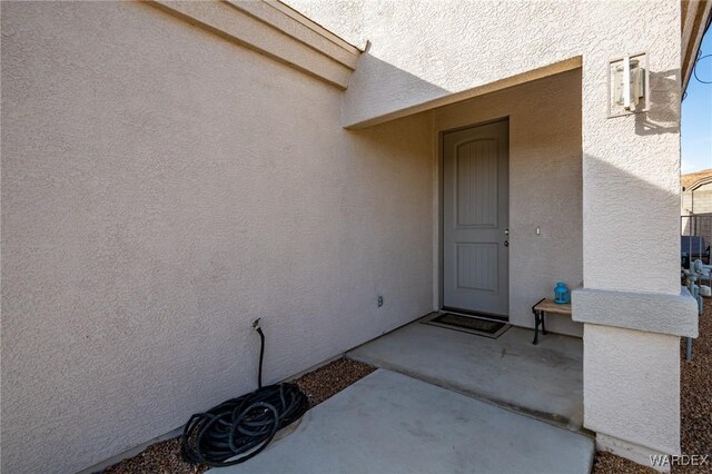 property entrance with a patio area and stucco siding