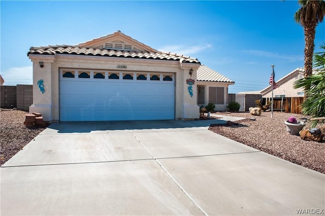 mediterranean / spanish house featuring an attached garage, driveway, a tiled roof, and stucco siding