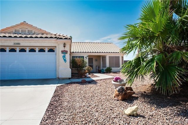 view of front facade featuring a garage, concrete driveway, a tiled roof, and stucco siding