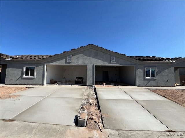 view of front of property with stucco siding, a tiled roof, driveway, and a garage