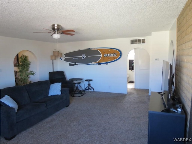 living area with visible vents, arched walkways, a ceiling fan, carpet, and a textured ceiling