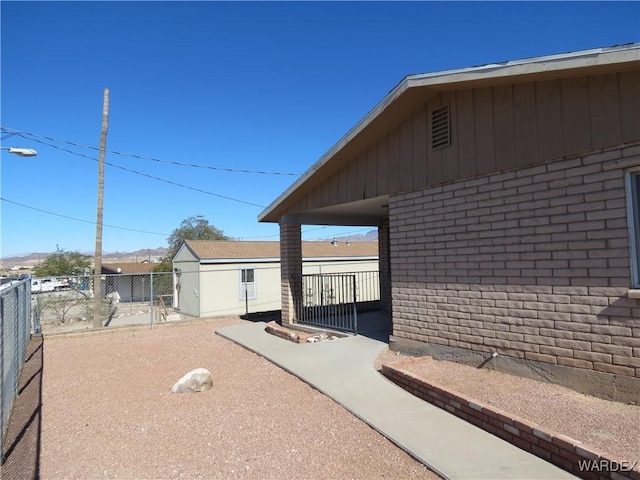 view of side of property with brick siding and fence