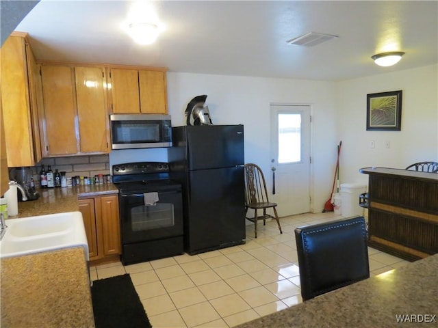 kitchen with black appliances, visible vents, brown cabinets, and a sink