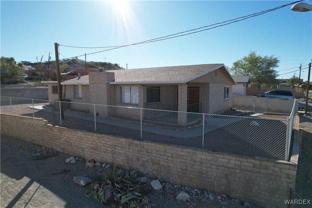 view of front of house featuring fence private yard, a shingled roof, and brick siding