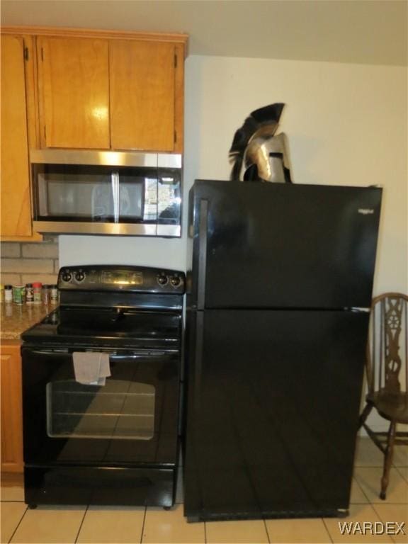 kitchen featuring brown cabinets, black appliances, and light tile patterned floors