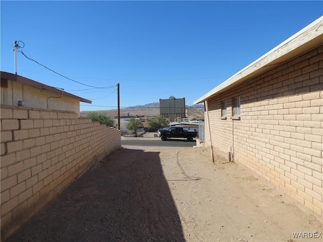 view of side of home featuring fence and brick siding