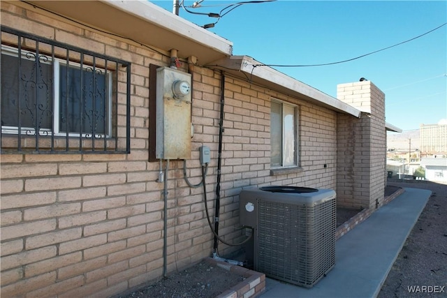 view of home's exterior featuring cooling unit, brick siding, and a chimney