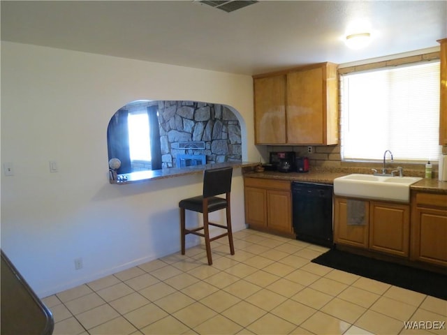 kitchen with black dishwasher, brown cabinetry, a sink, and a healthy amount of sunlight