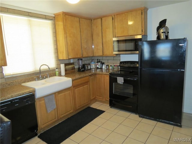 kitchen featuring light countertops, light tile patterned flooring, a sink, and black appliances