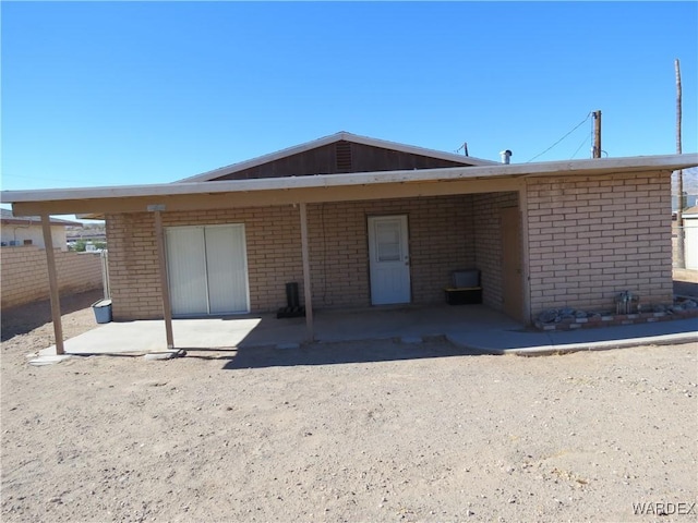 rear view of property with brick siding and a patio