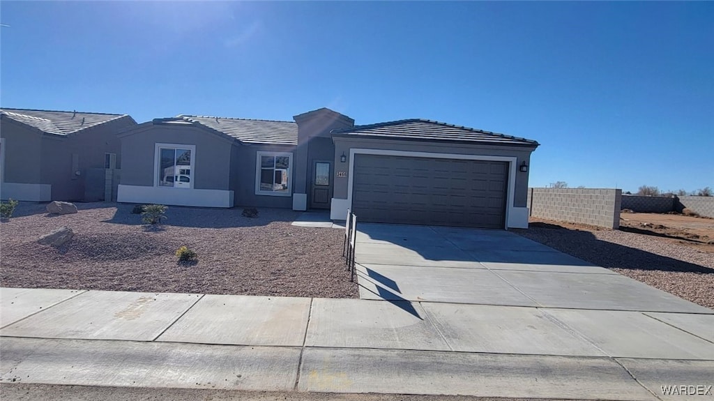 ranch-style home featuring driveway, a tile roof, an attached garage, fence, and stucco siding