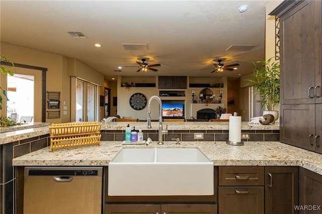 kitchen featuring open floor plan, stainless steel dishwasher, a sink, and dark brown cabinetry