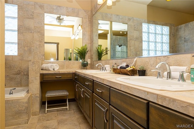 full bathroom featuring ceiling fan, a sink, and tile walls