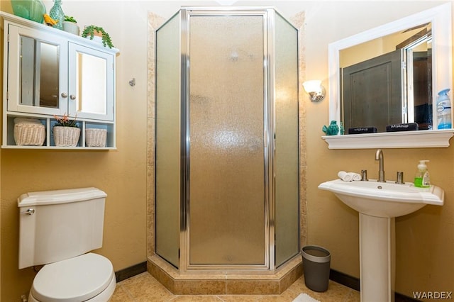 full bath with a stall shower, tile patterned floors, toilet, and baseboards