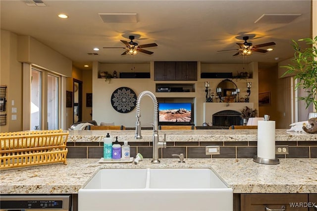 kitchen with dishwasher, a fireplace, open floor plan, and a sink