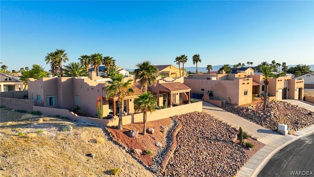 pueblo-style home with a residential view, fence, and stucco siding