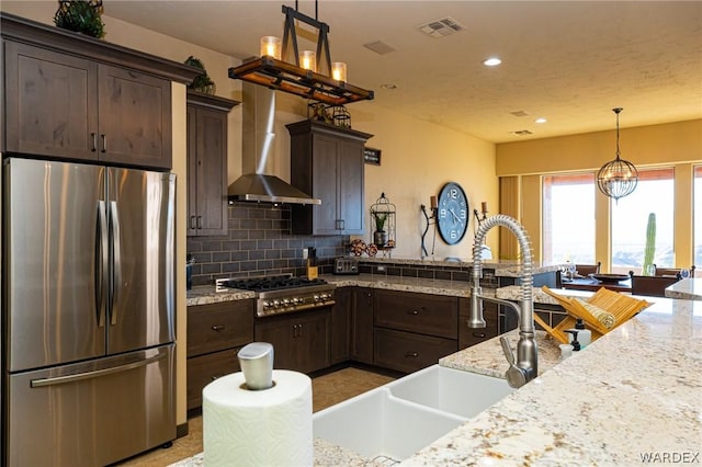 kitchen with appliances with stainless steel finishes, visible vents, wall chimney exhaust hood, and light stone countertops