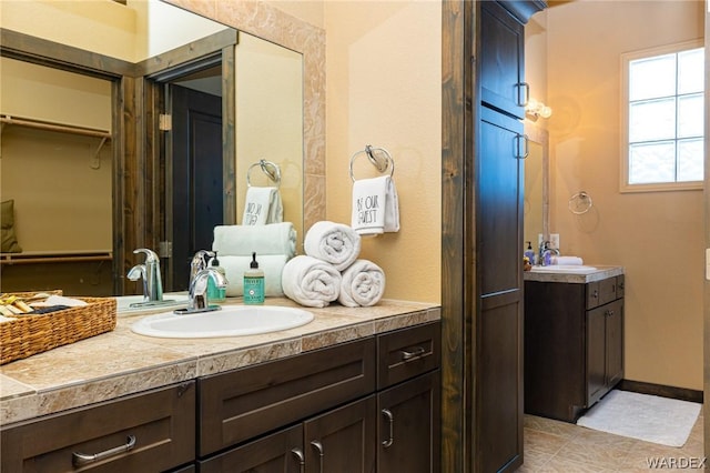 full bath with a walk in closet, vanity, and baseboards