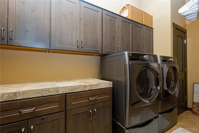 clothes washing area with separate washer and dryer and cabinet space