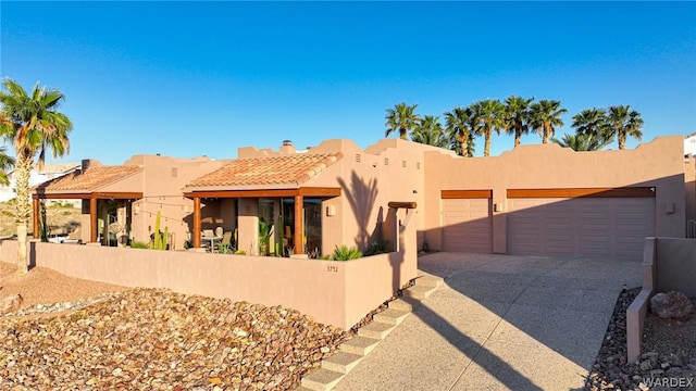 southwest-style home with driveway, a fenced front yard, an attached garage, and stucco siding