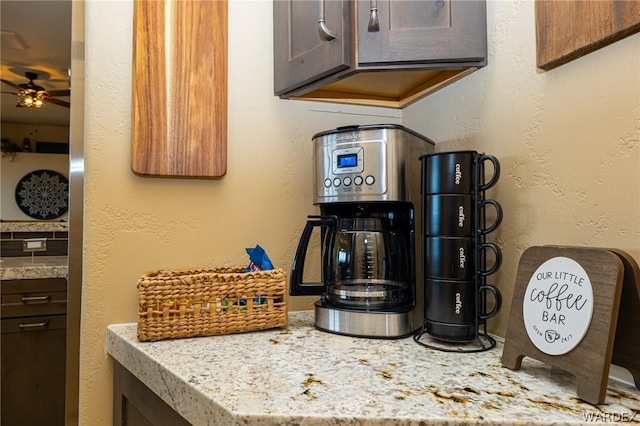 room details with light stone countertops, dark brown cabinetry, a ceiling fan, and a textured wall