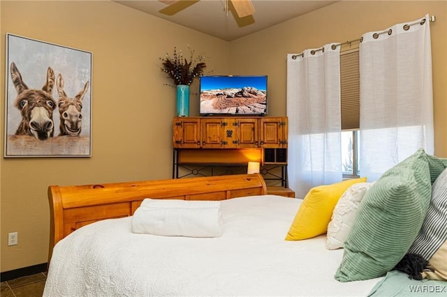 bedroom featuring a ceiling fan, dark tile patterned flooring, and baseboards