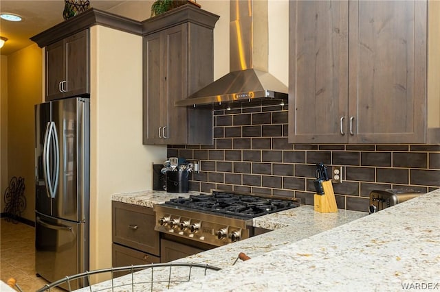 kitchen with appliances with stainless steel finishes, backsplash, wall chimney range hood, and light stone countertops