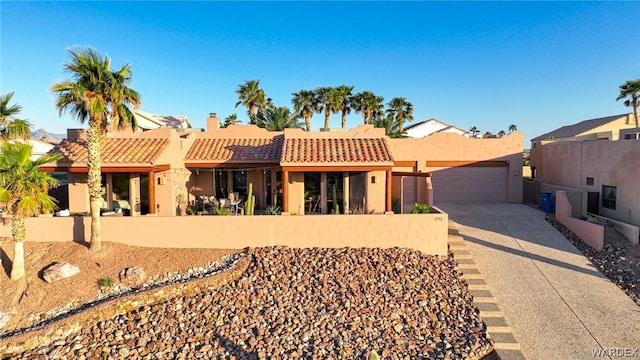 pueblo-style house with driveway, fence, and stucco siding