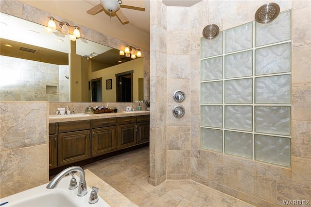 bathroom featuring visible vents, double vanity, a sink, and tile walls