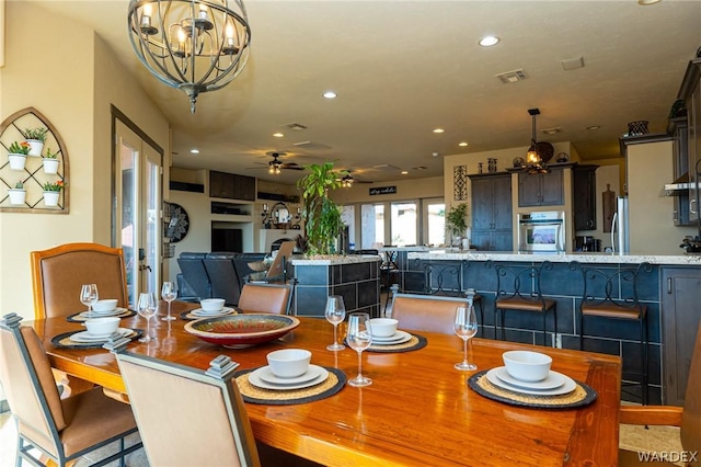 dining room featuring recessed lighting, visible vents, a fireplace, and ceiling fan with notable chandelier