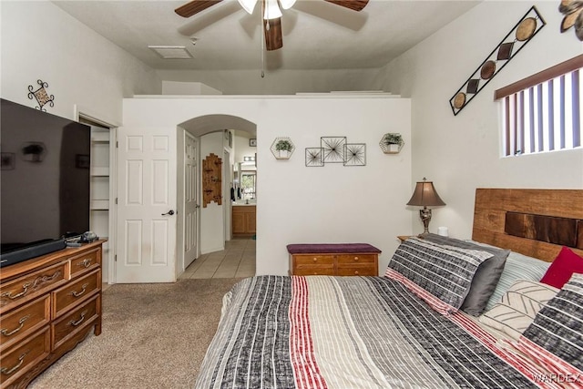 2355 Morningside Dr, Bullhead City, AZ 86442 - bedroom featuring light tile patterned flooring, ensuite bath, a ceiling fan, light carpet, and arched walkways