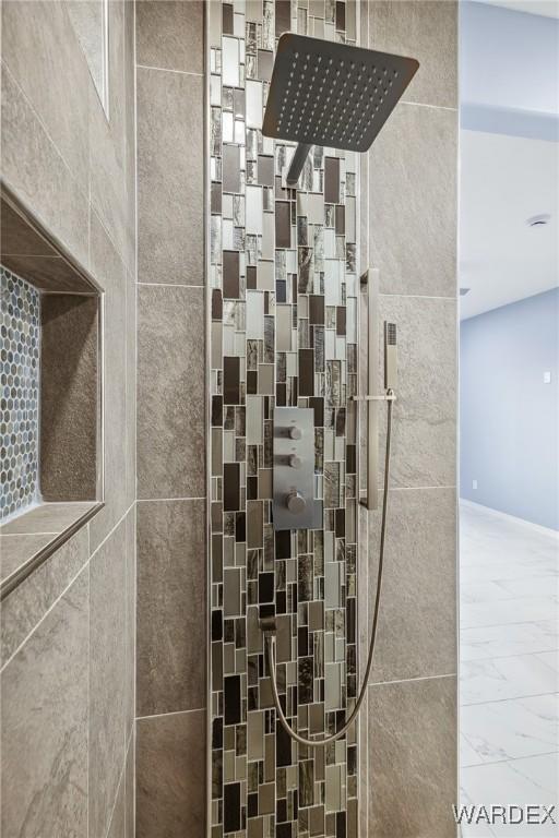 full bathroom featuring marble finish floor and tiled shower