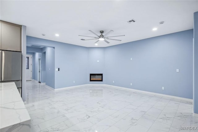 unfurnished living room with a glass covered fireplace, marble finish floor, visible vents, and baseboards