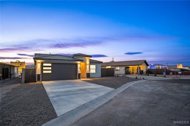 view of front facade featuring a garage, concrete driveway, fence, and stucco siding