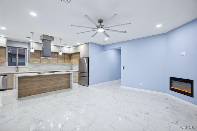 kitchen with stainless steel appliances, light countertops, modern cabinets, island exhaust hood, and decorative light fixtures