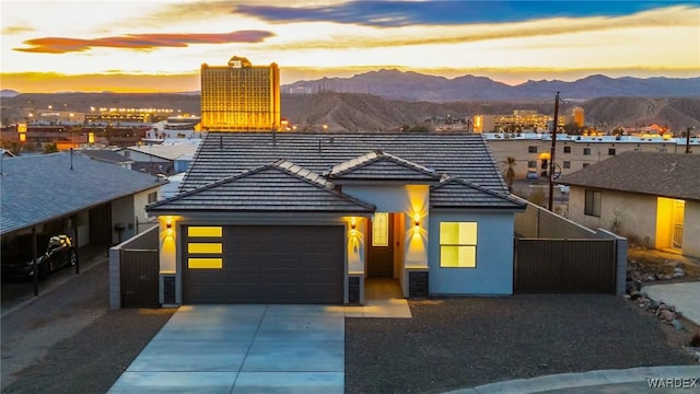 view of front of property featuring a tile roof, stucco siding, an attached garage, a mountain view, and driveway